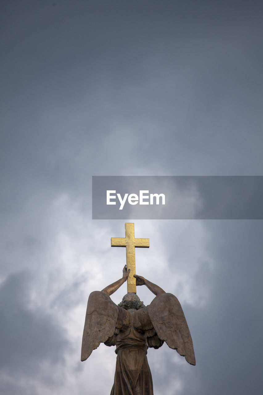 Low angle view of cross sculpture against sky