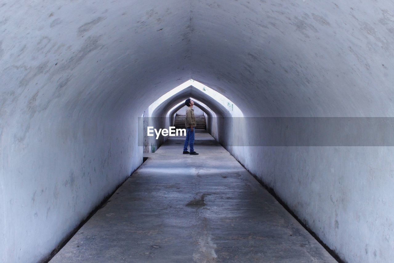 Side view of young man standing in tunnel