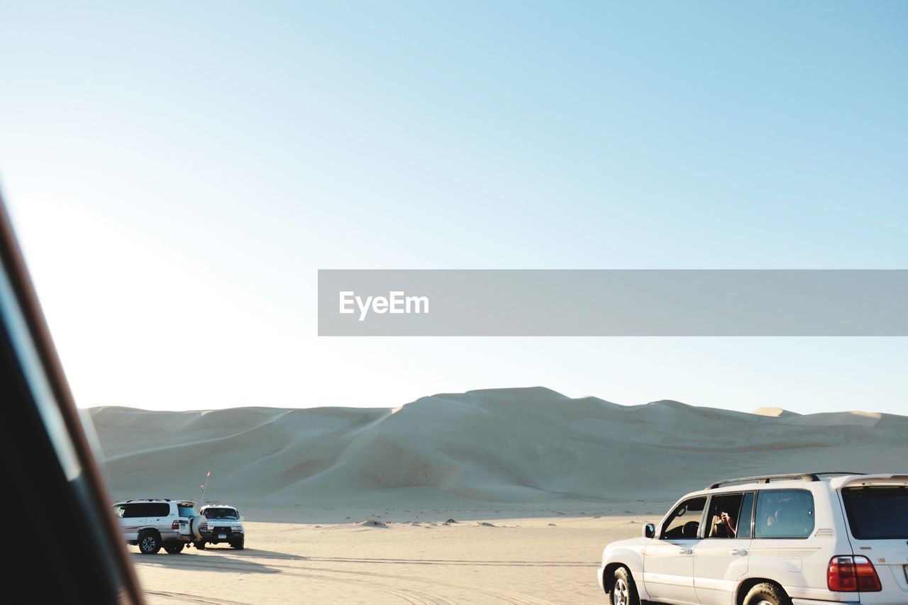 Off-road vehicles on desert against clear blue sky
