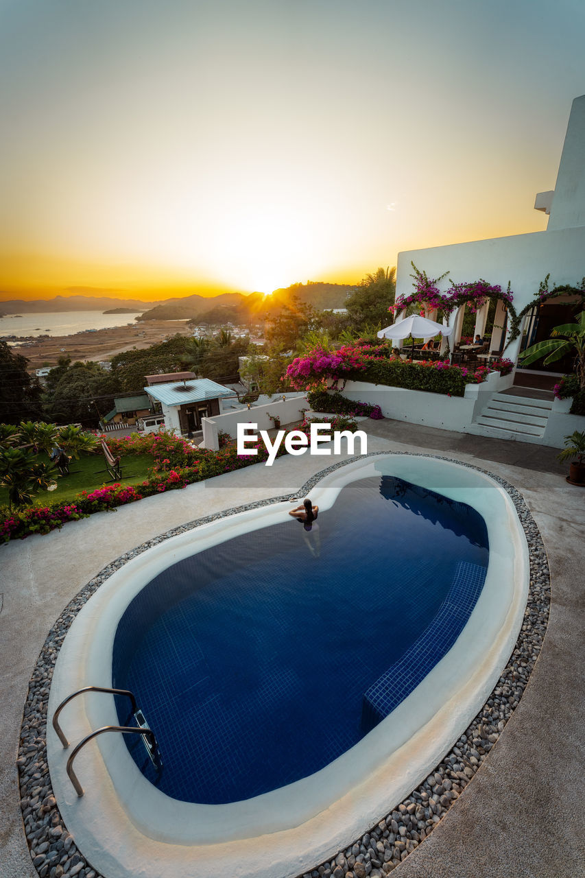 swimming pool, architecture, water, sunset, sky, nature, built structure, building exterior, travel destinations, building, city, estate, high angle view, outdoors, no people, luxury, residential district, sunlight, dusk, house, travel, wealth, tranquility, sports, beauty in nature