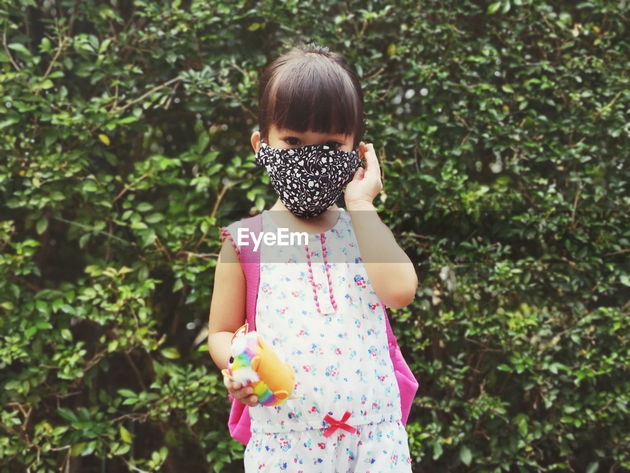 GIRL STANDING AGAINST PLANTS