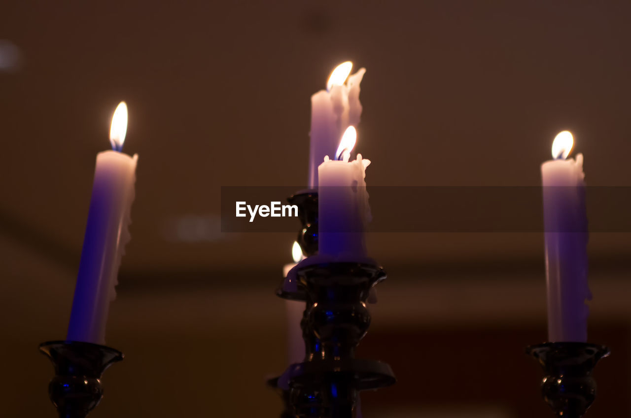 Close-up of lit candles against wall