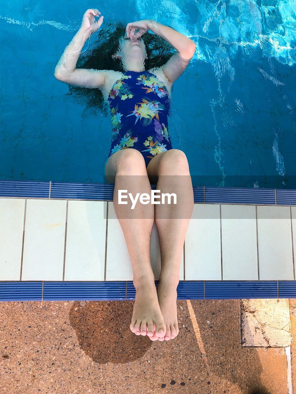 MIDSECTION OF WOMAN SITTING IN SWIMMING POOL