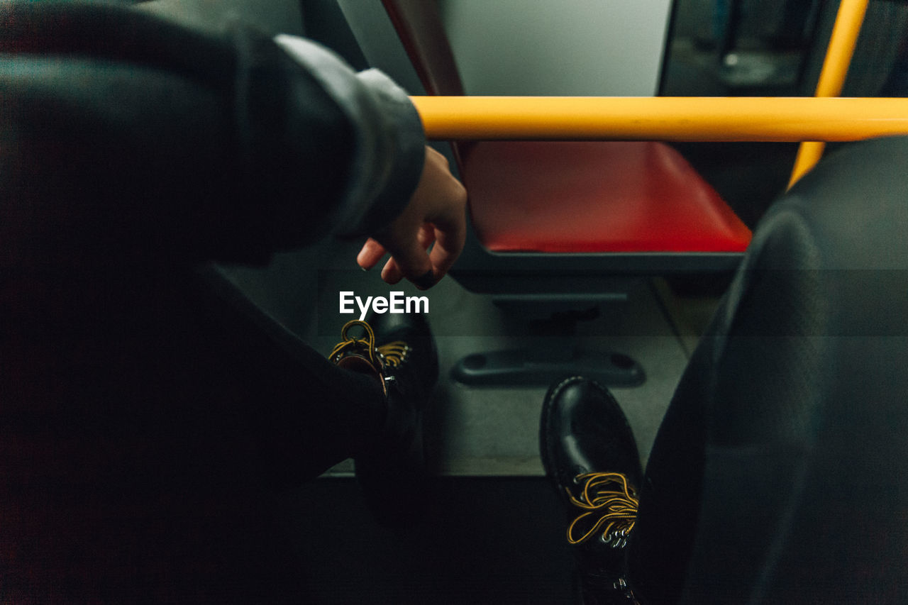 Low section of man wearing shoes in bus