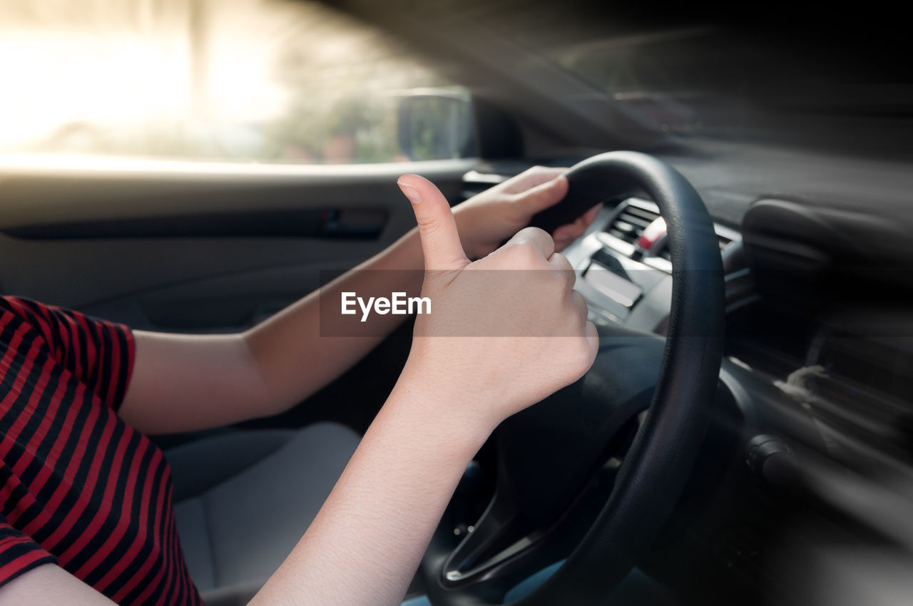 Midsection of woman gesturing while driving car