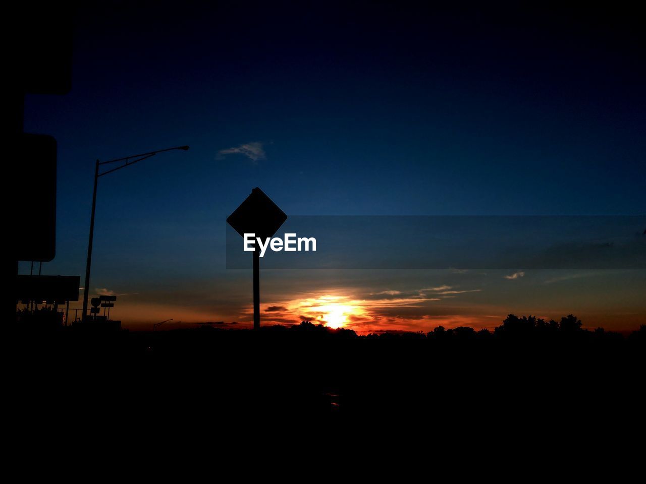 Silhouette road sign against sky during sunset