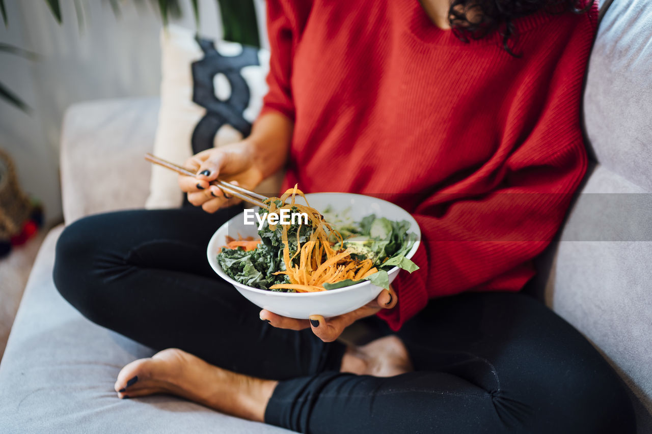 Brunette woman eating a healthy green salad.