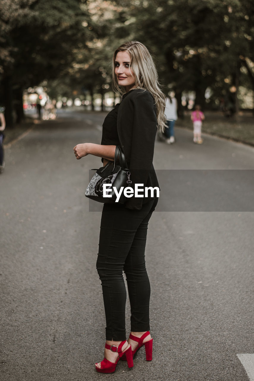 Full length side view portrait of woman standing on road