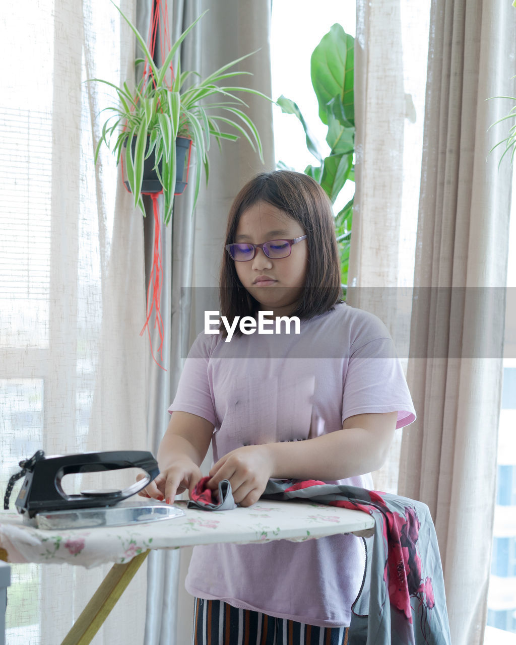 Girl pressing clothes at home