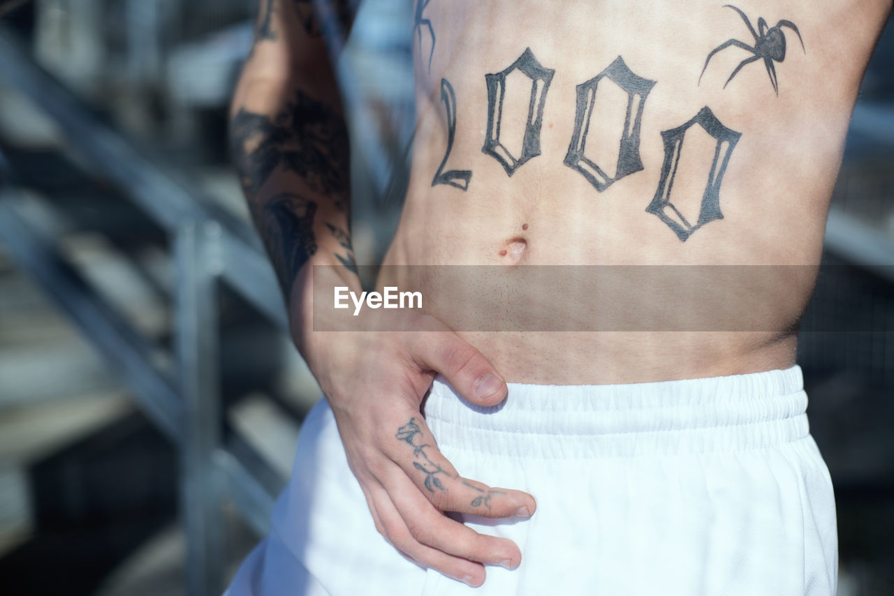 Midsection of shirtless man with tattoo