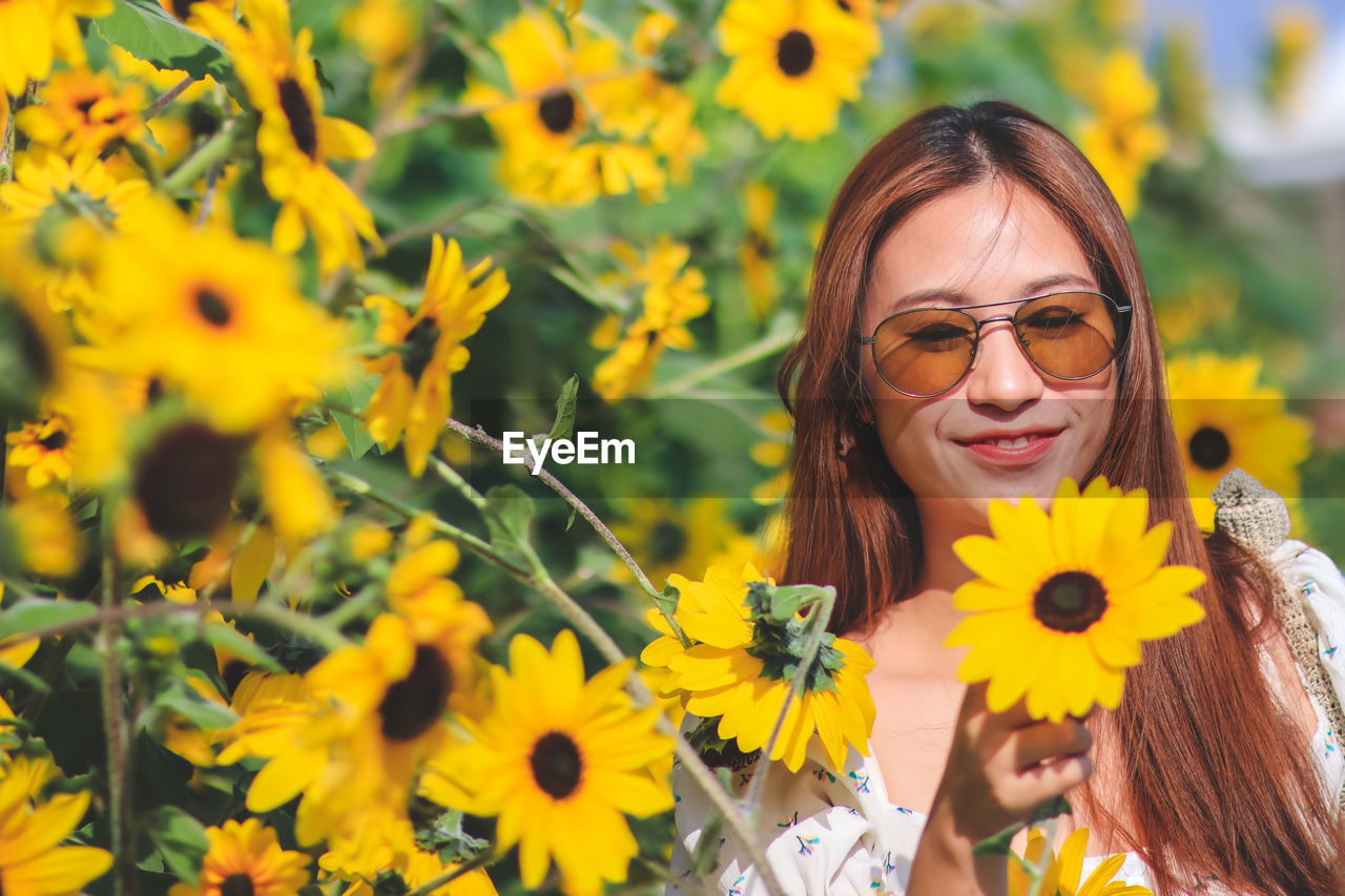 Portrait of smiling woman with yellow flowers