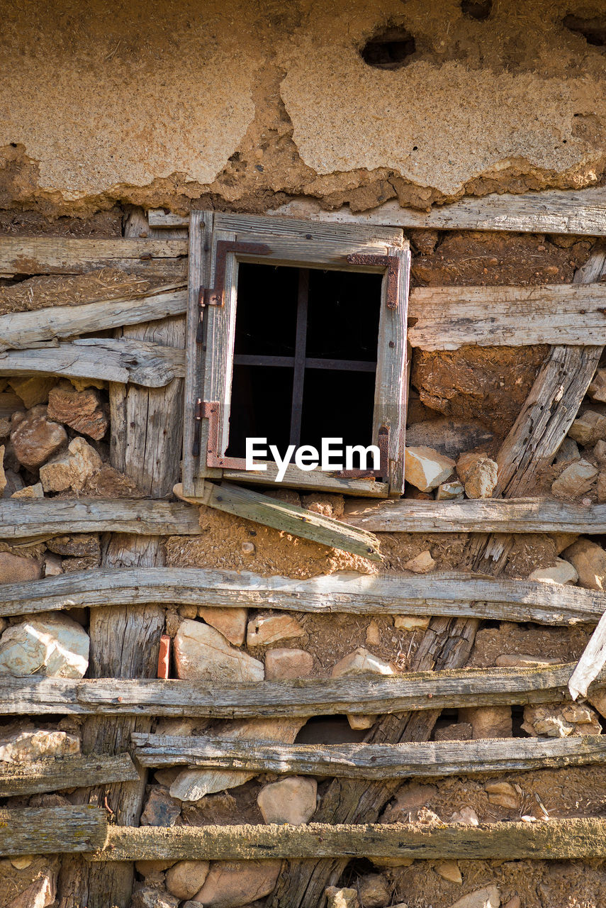 LOW ANGLE VIEW OF WEATHERED WINDOW ON OLD HOUSE