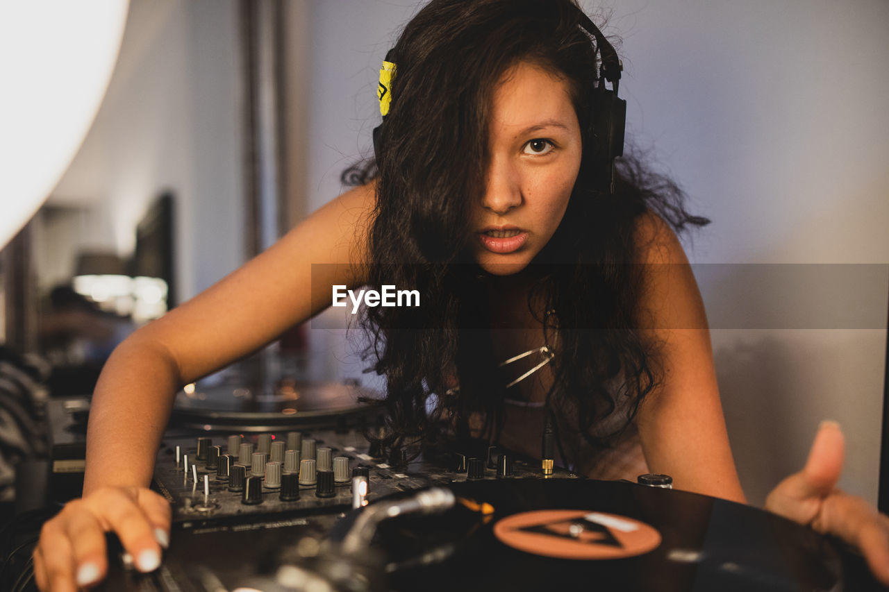 Close-up of fashionable young woman playing music at home