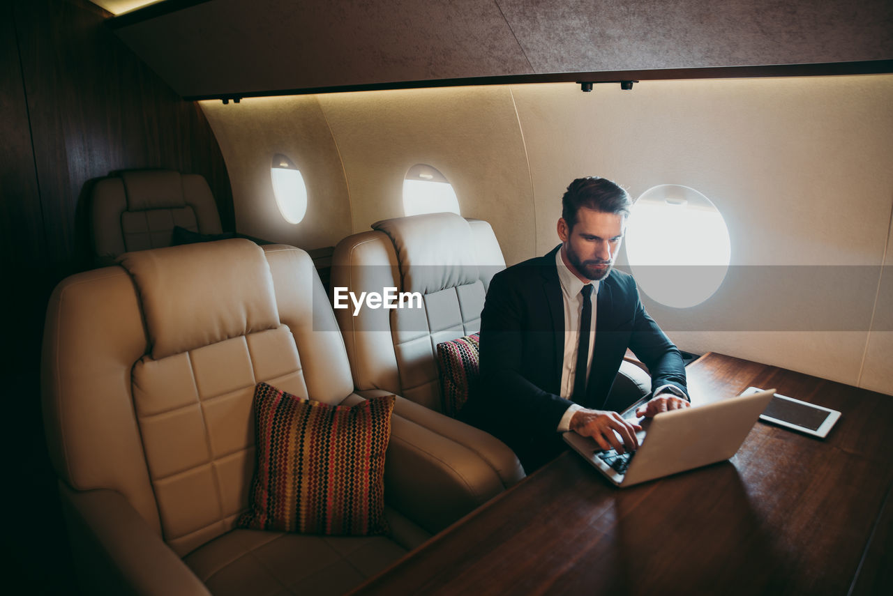 Businessman using laptop in airplane