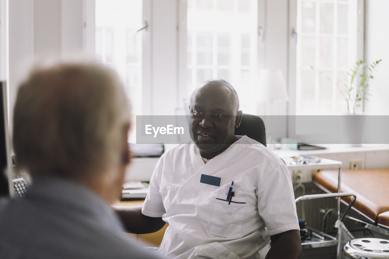 Mature male doctor advising patient during visit in clinic