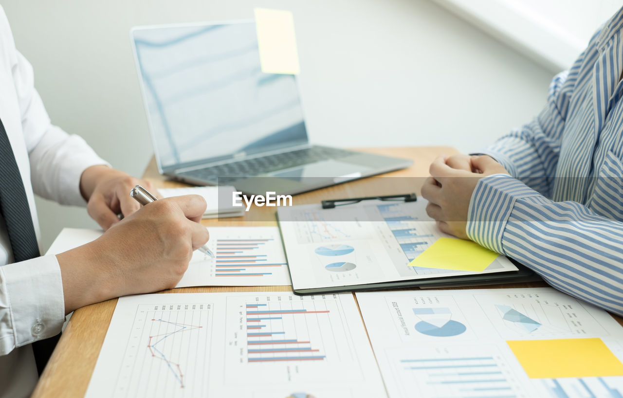 Midsection of business colleagues working on table