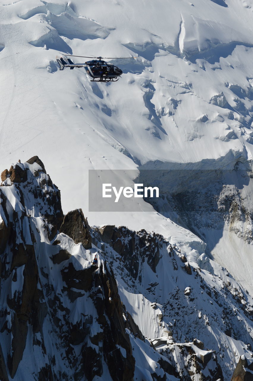 Scenic view of snowcapped mountains against sky with rescue helicopter