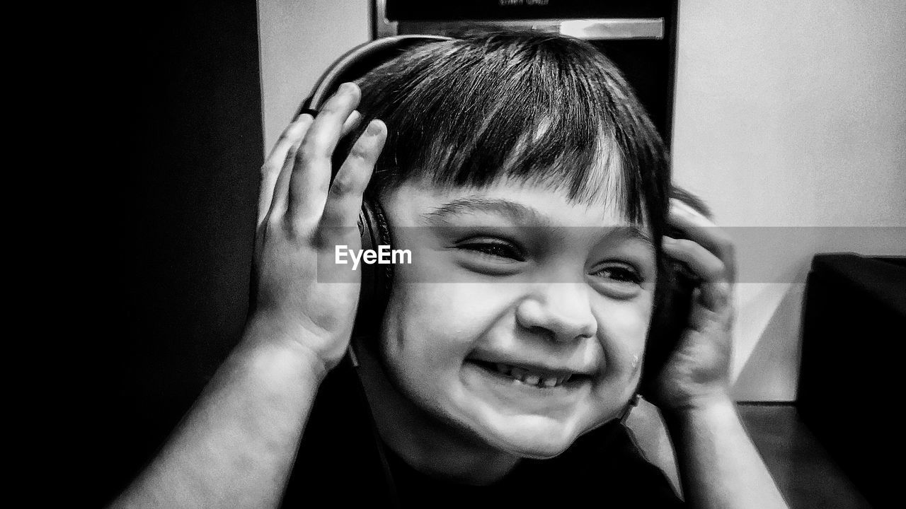 Close-up of smiling boy listening music at home
