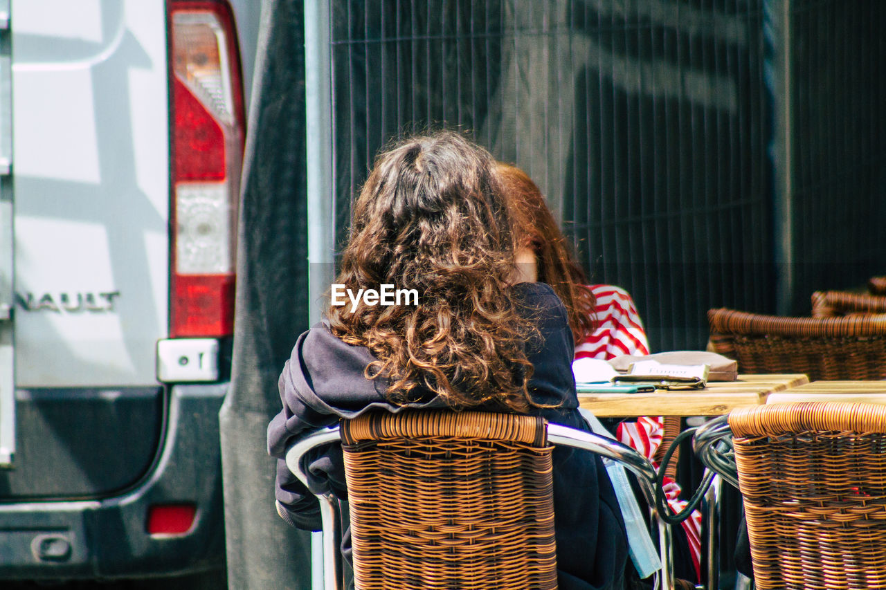 REAR VIEW OF WOMAN SITTING AT BUS