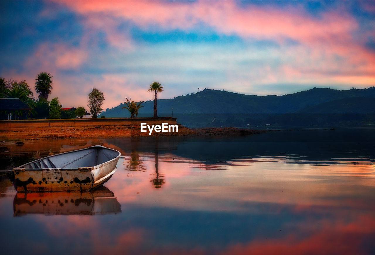 Twilight reflected in lake and a beached boat 