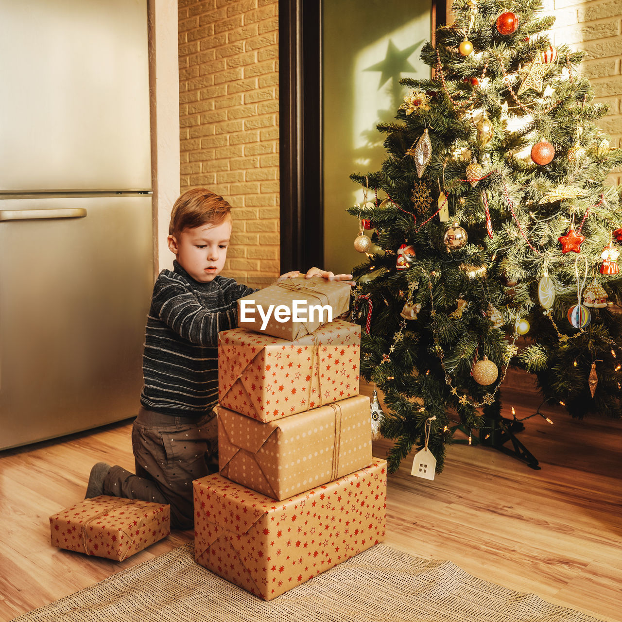 Boy arranging gifts by christmas tree at home