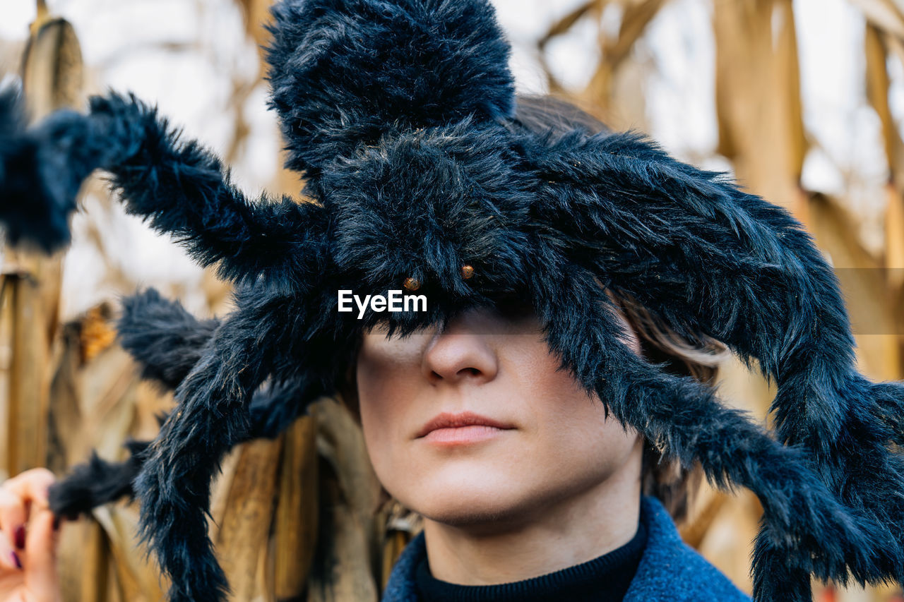 Huge black shaggy toy spider on woman's head closes her eyes. halloween party decorations