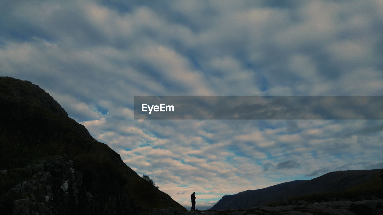 SILHOUETTE OF MAN IN CLOUDY SKY