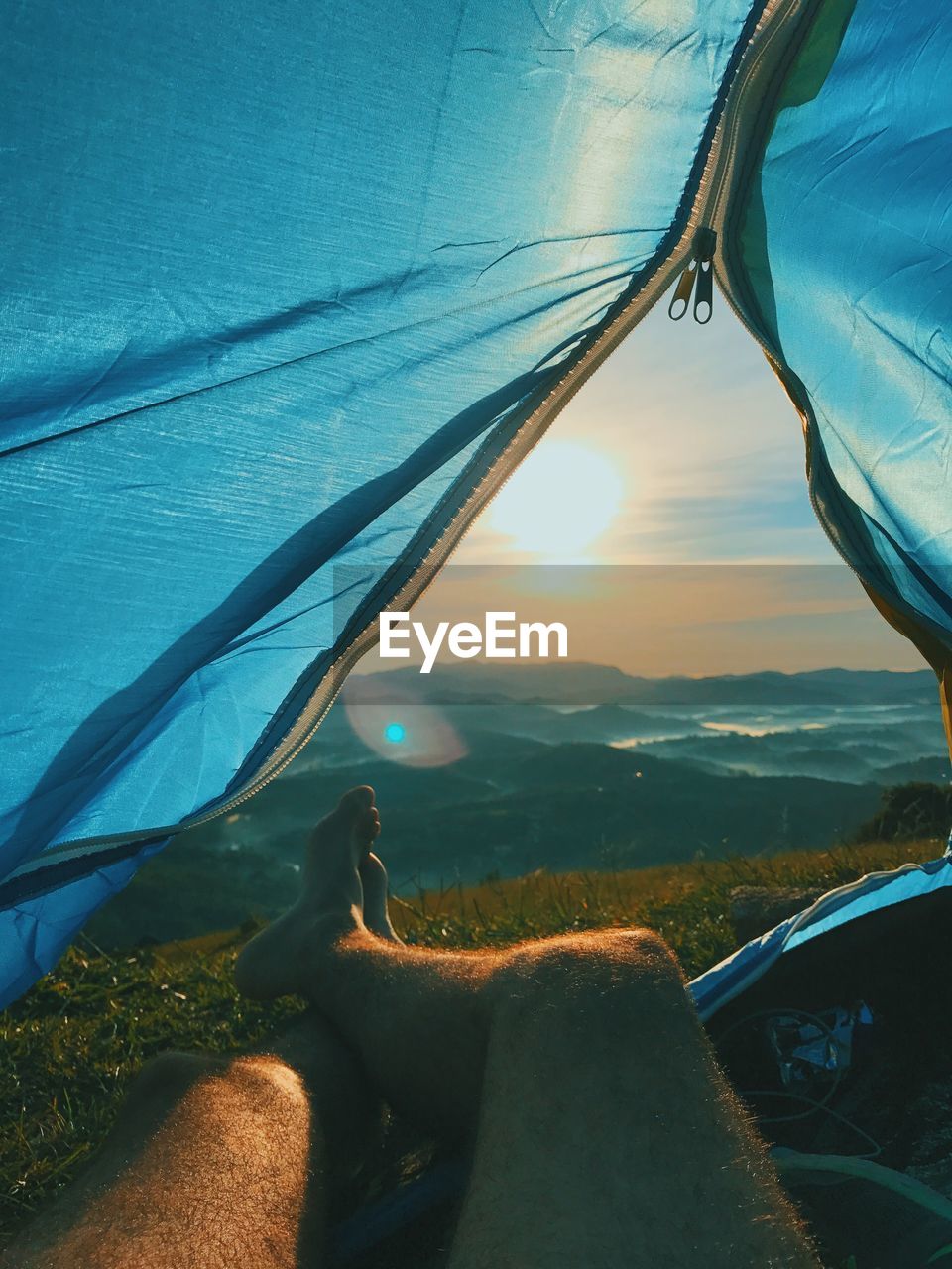 Low section of man relaxing in tent at sunset