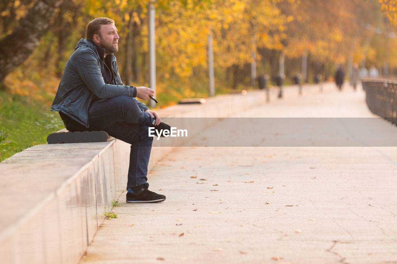 Mature man smoking while sitting on bench at park