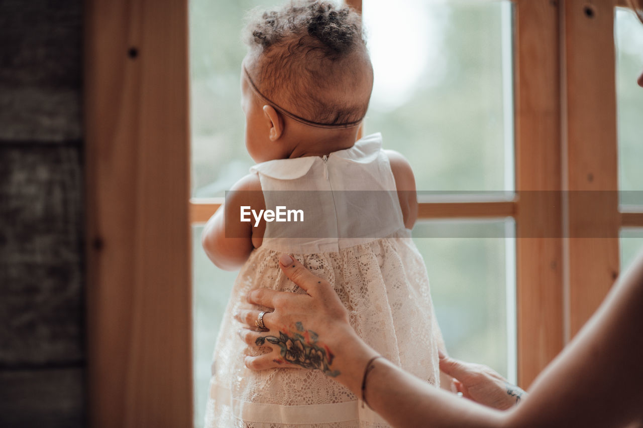 Woman looking through window at home