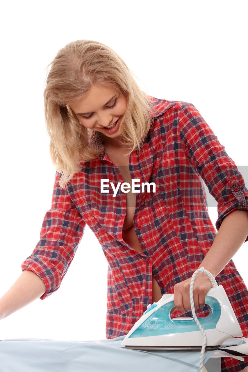 Woman ironing clothes against white background