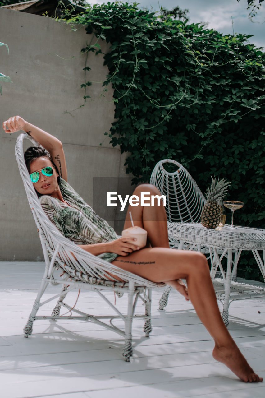 Woman sitting on chair at swimming pool