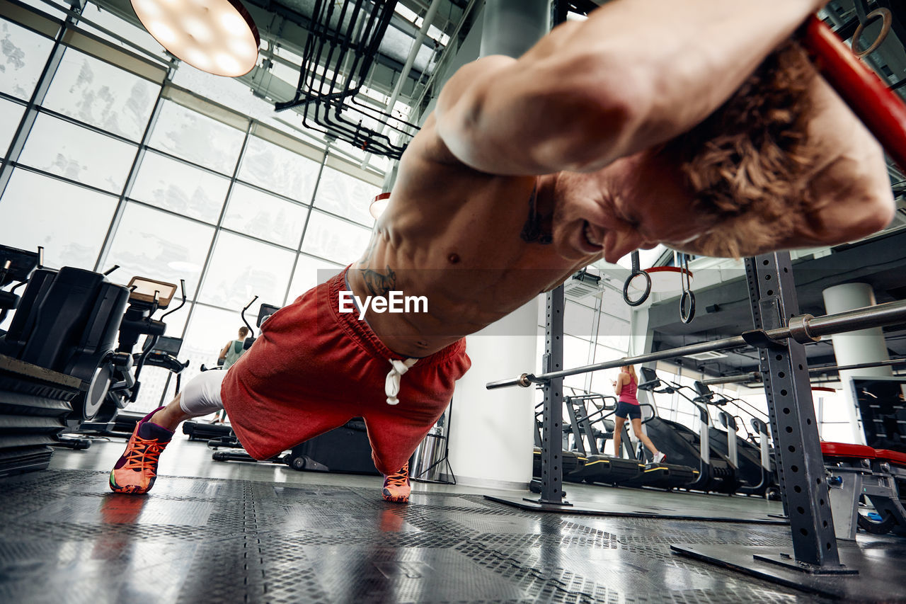 Full length of muscular man working out at gym