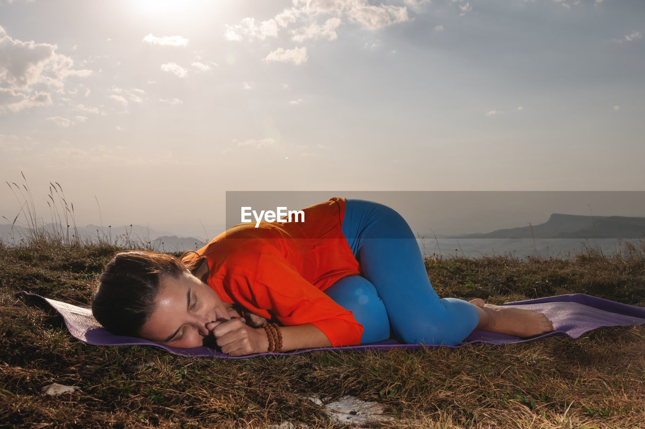 Side view of a beautiful young happy athletic woman in a sport sweatshirt and blue yoga pants