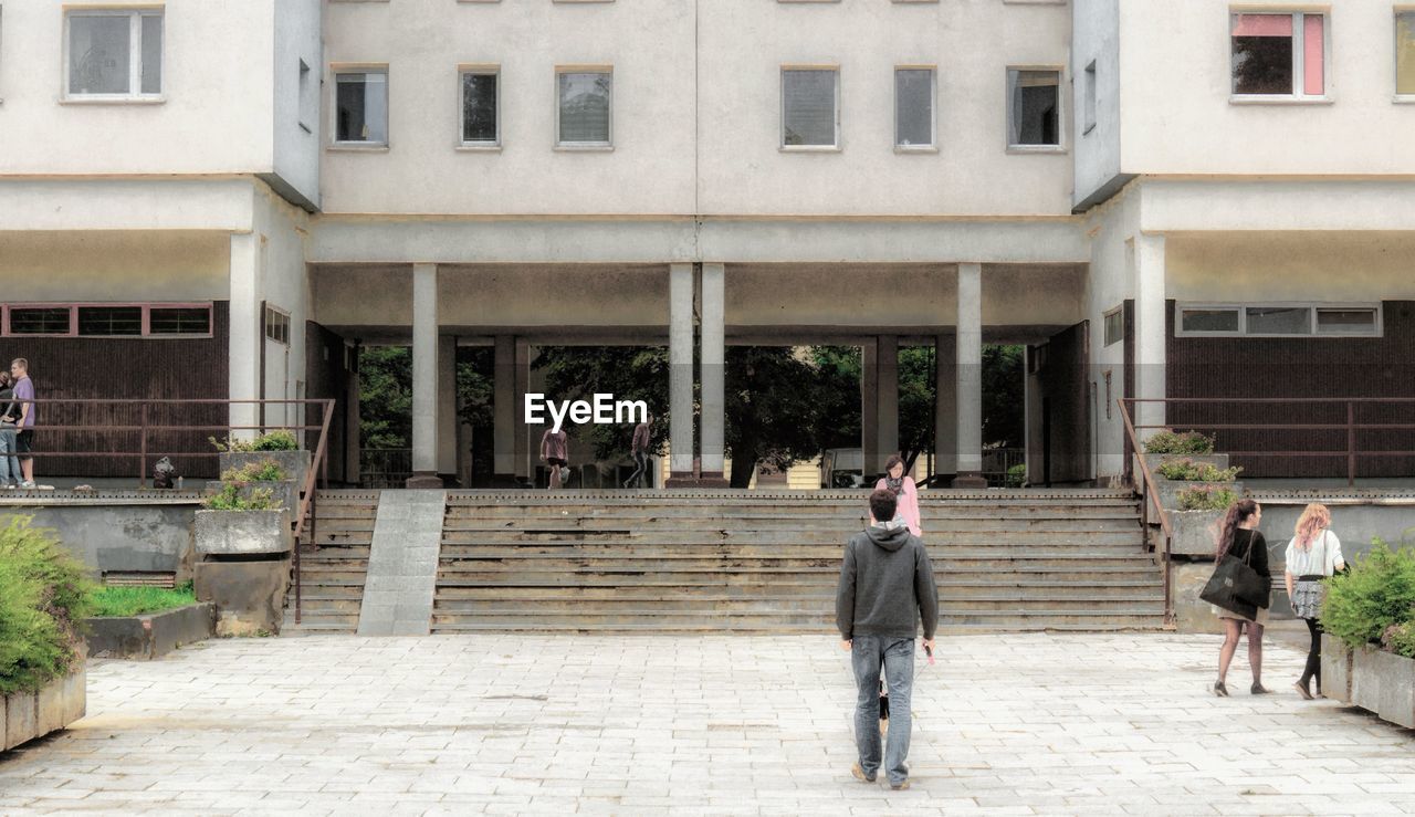 REAR VIEW OF PEOPLE WALKING ON BUILDING