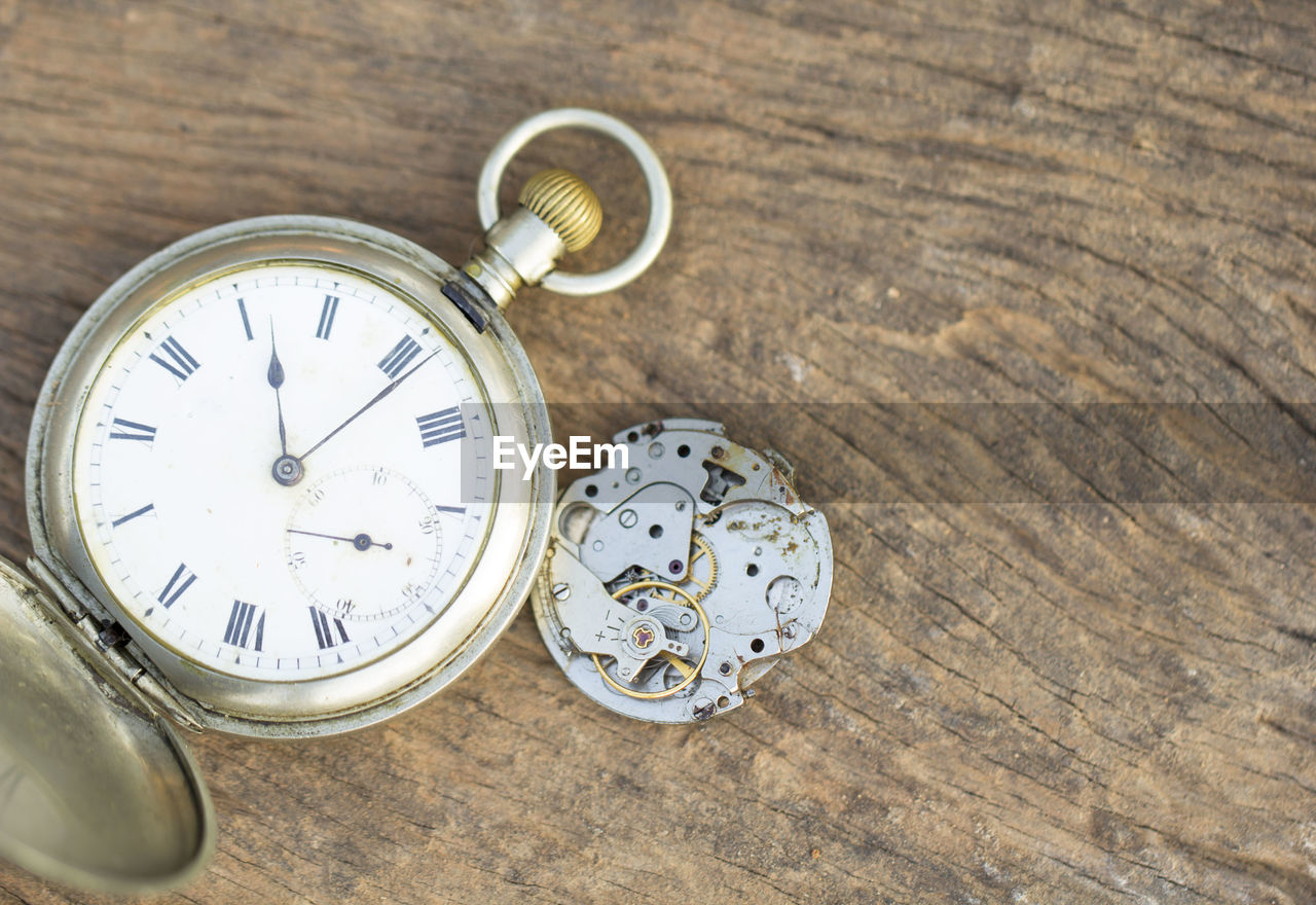 High angle view of broken pocket watch on wooden table