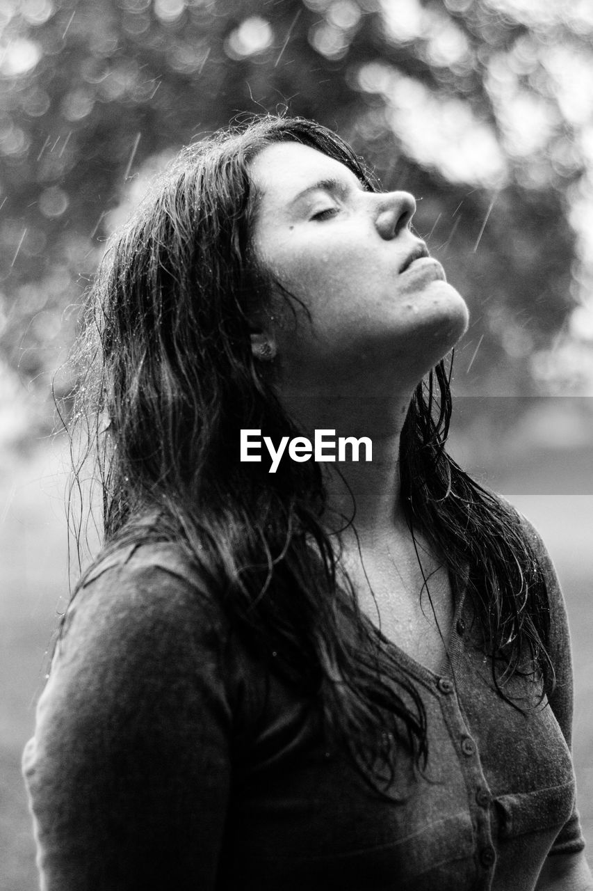 Woman with closed eyes standing outdoors during rainy season