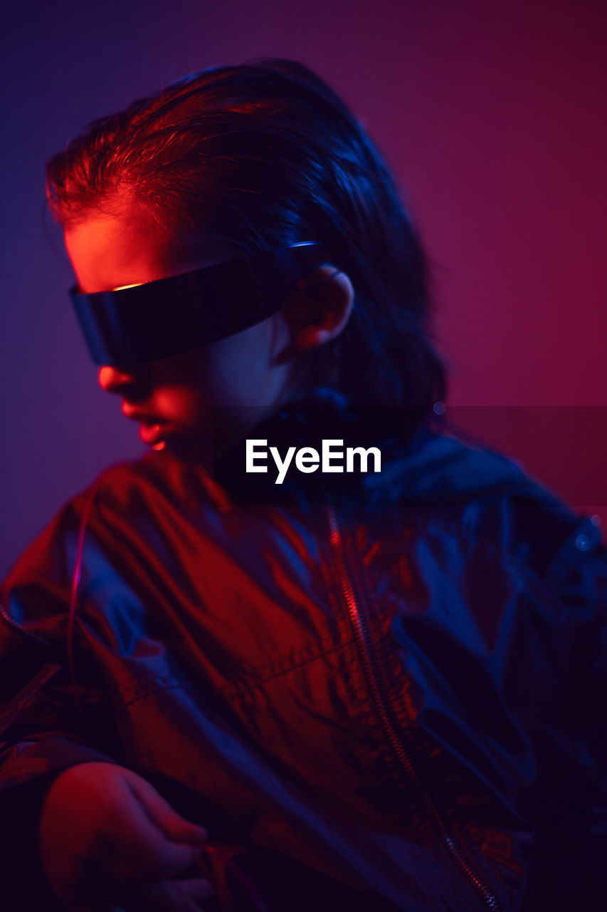 Portrait cyberpunk boy child in vr glasses in blue and red tones. game, virtual reality