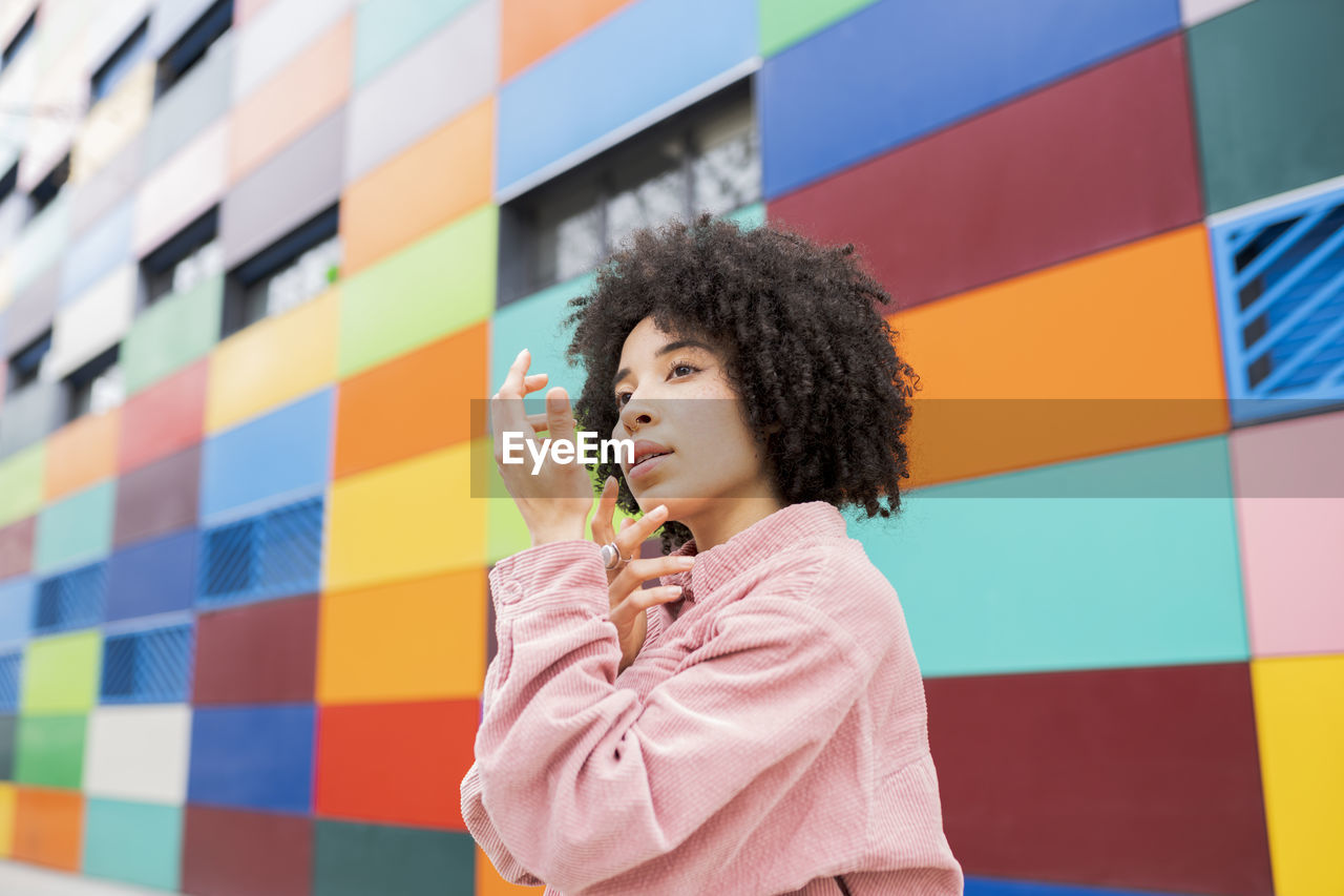 Young female dancer gesturing by colorful building