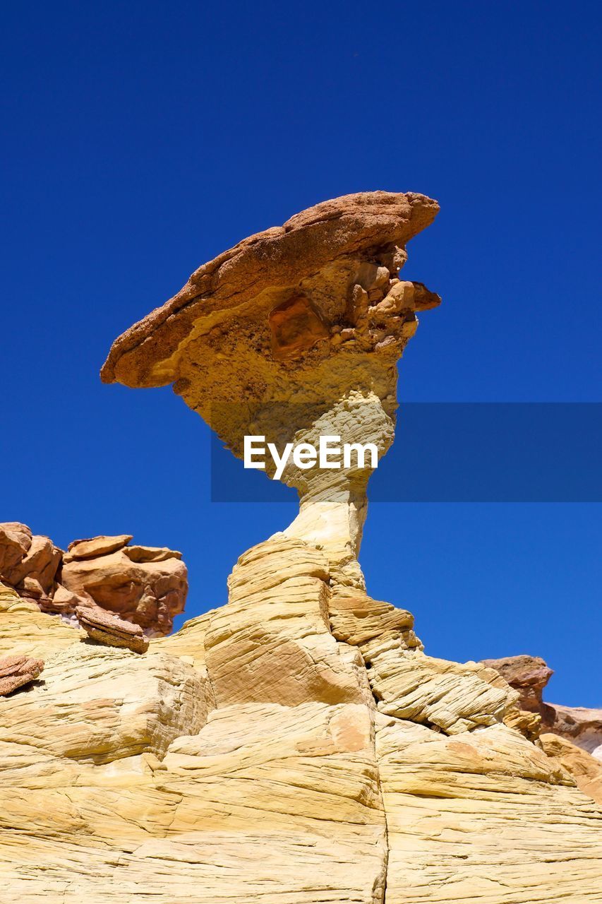 LOW ANGLE VIEW OF STATUE ON ROCK AGAINST BLUE SKY