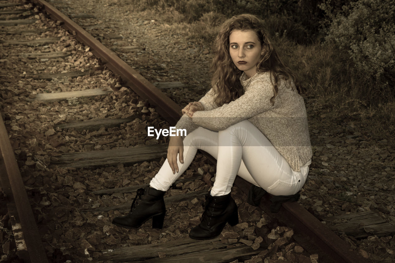 Thoughtful teenage girl sitting railroad track
