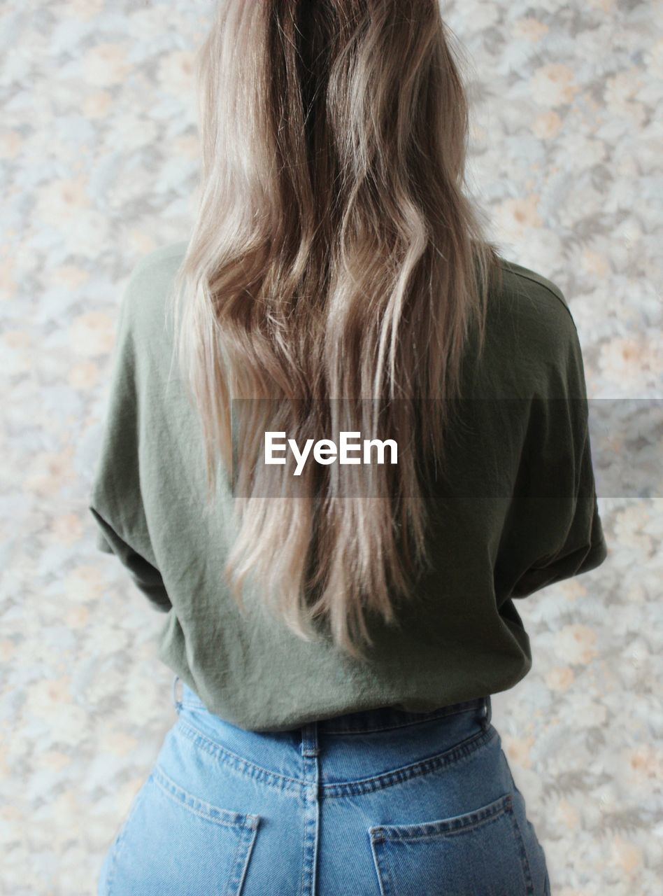 Rear view of woman standing against wall