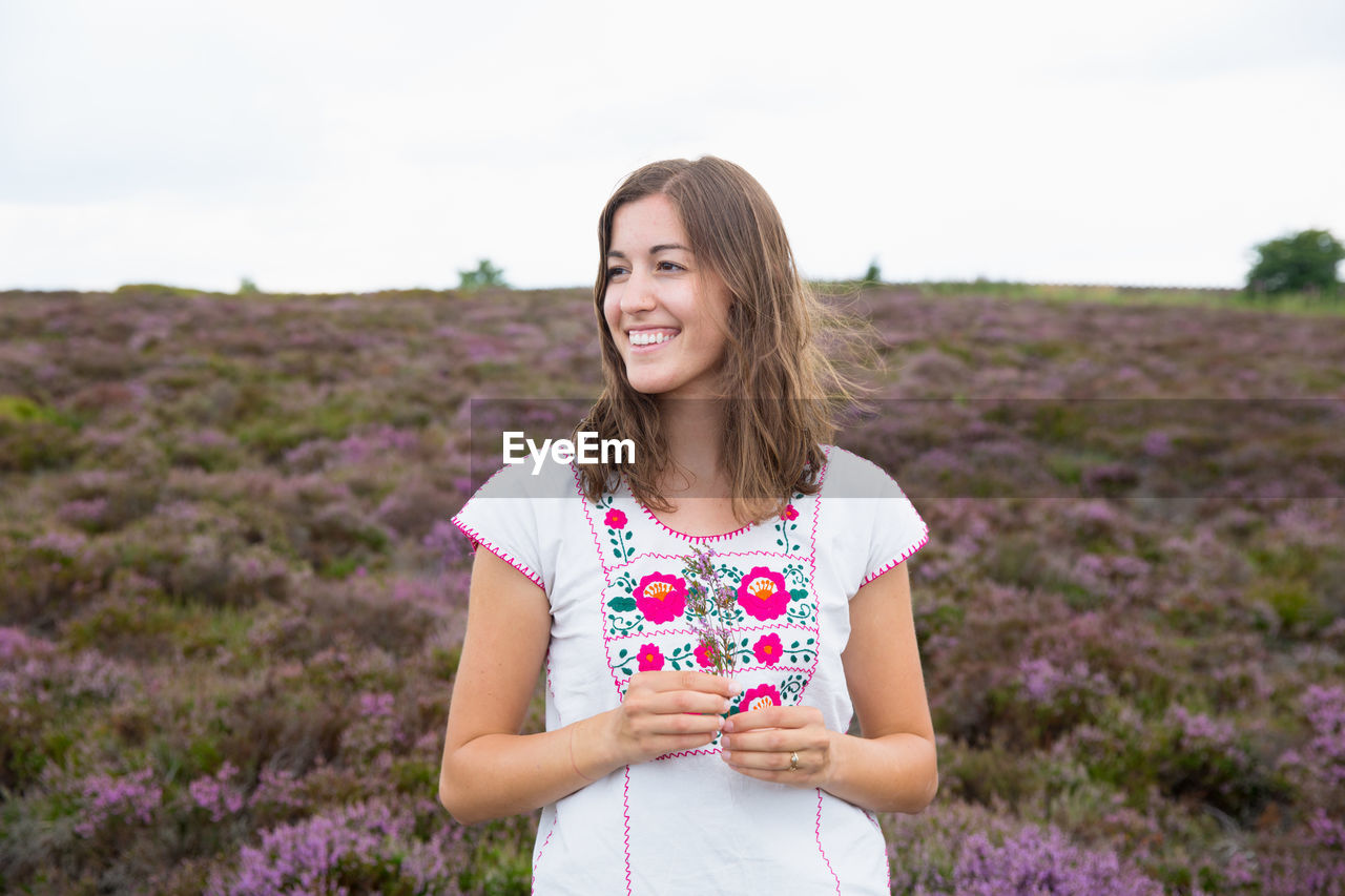Smiling young woman standing on field