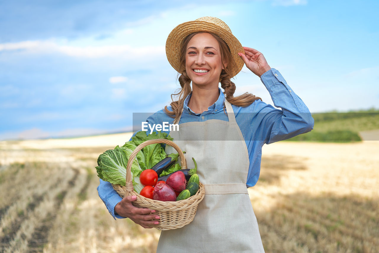 PORTRAIT OF SMILING YOUNG WOMAN HOLDING ICE CREAM CONE AT FARM