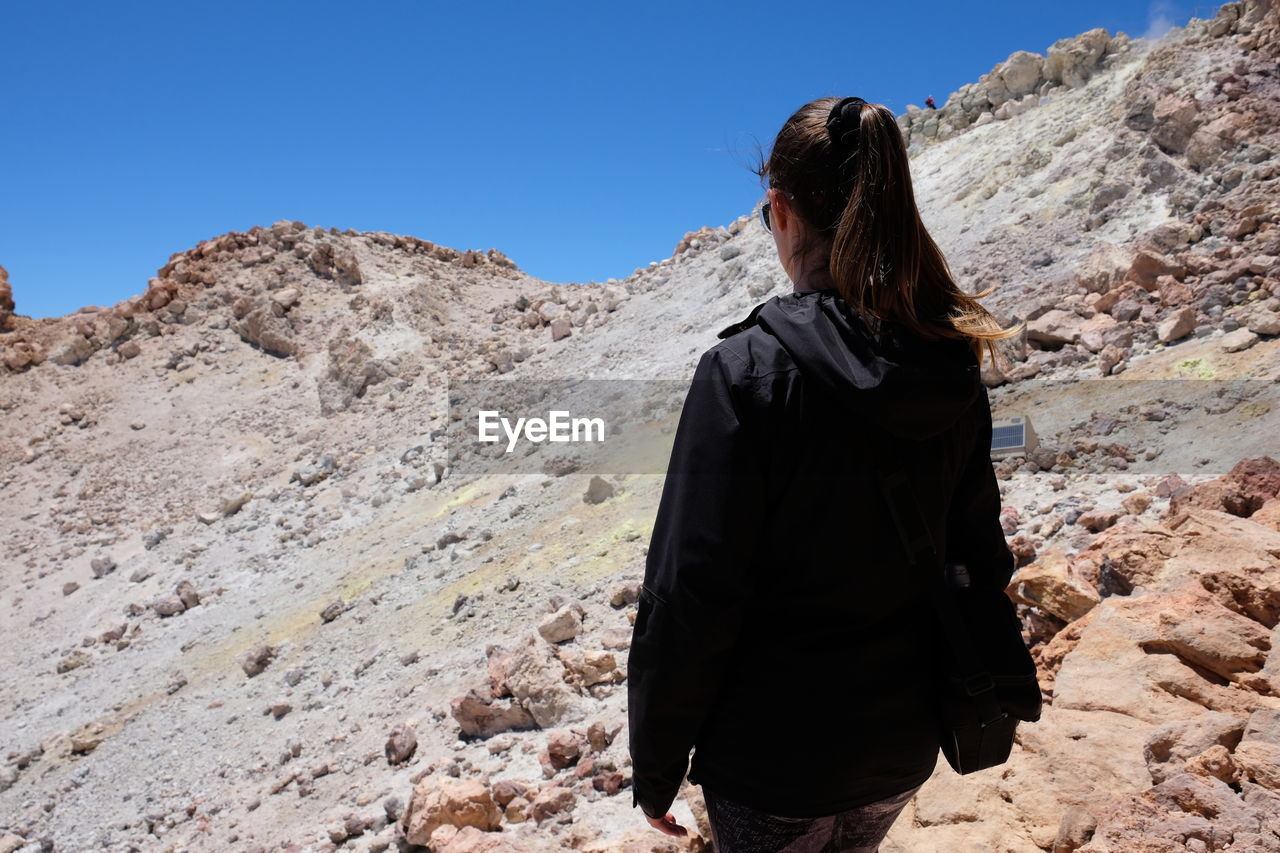 Rear view of woman standing on mountain against sky