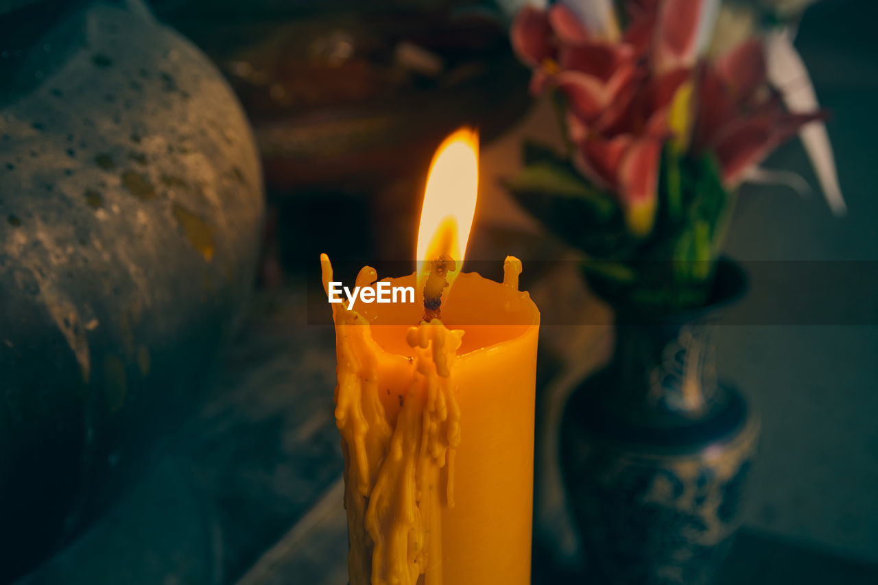 Large yellow candle and fire with flower background in vintage tone