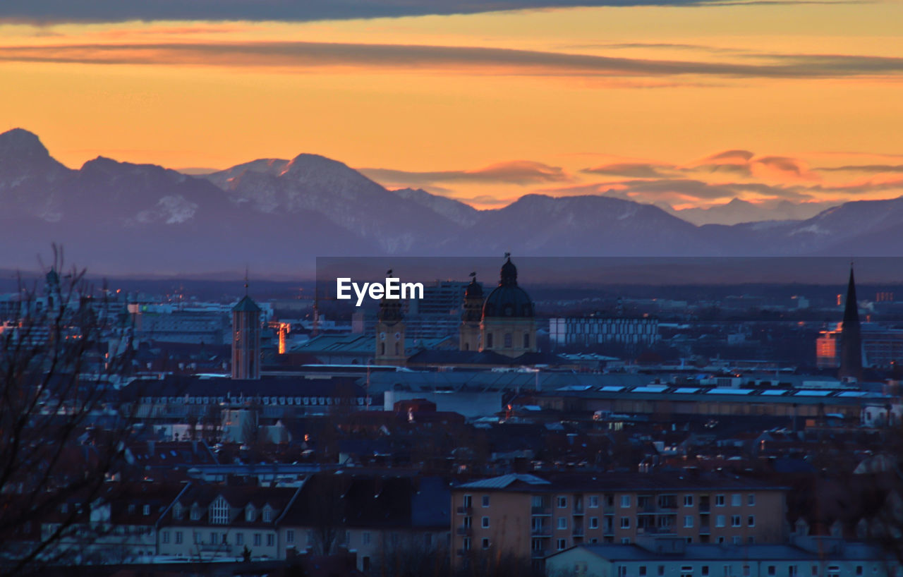 Townscape by mountains against sky at sunrise