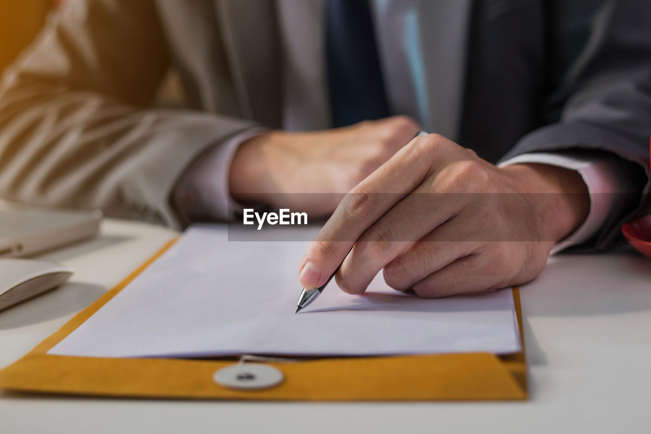 Midsection of man writing on paper