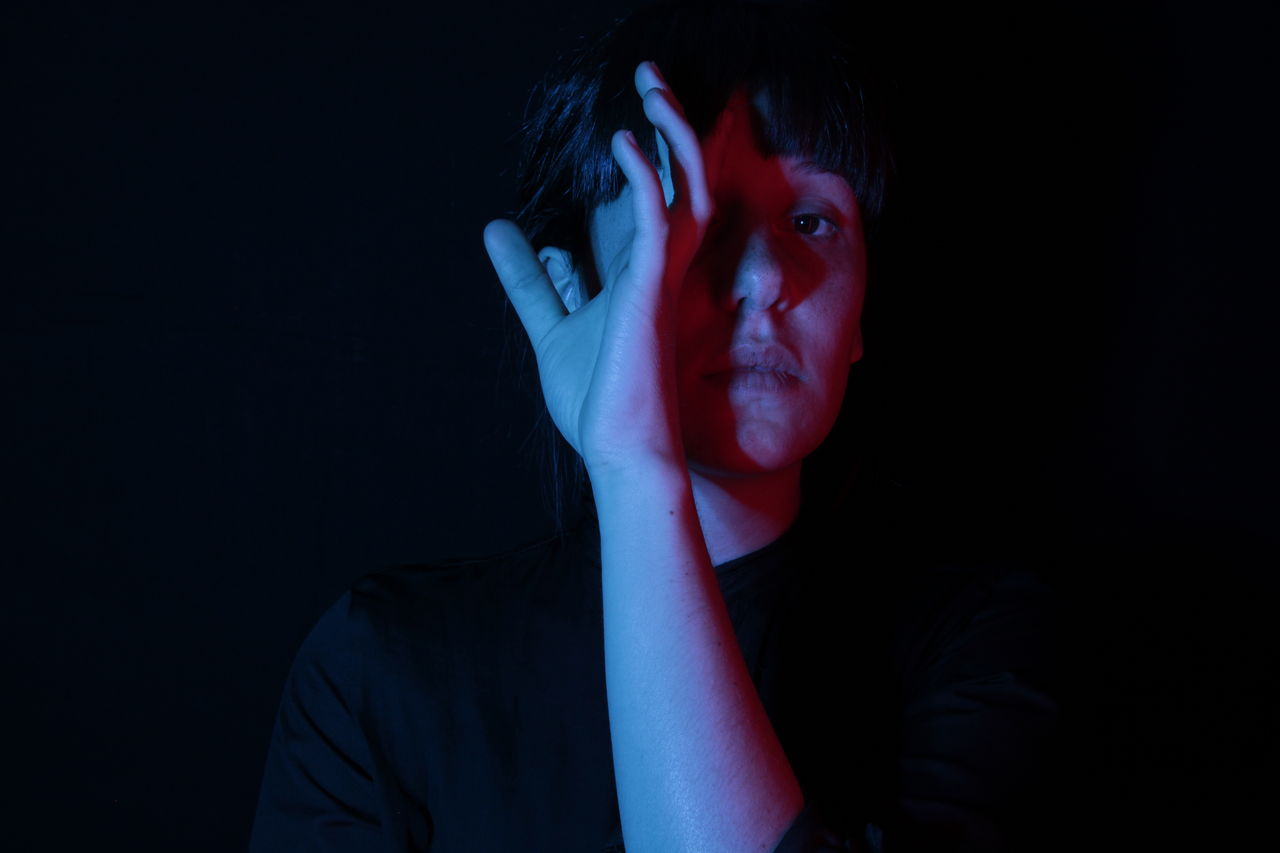 Portrait of serious young woman against black background