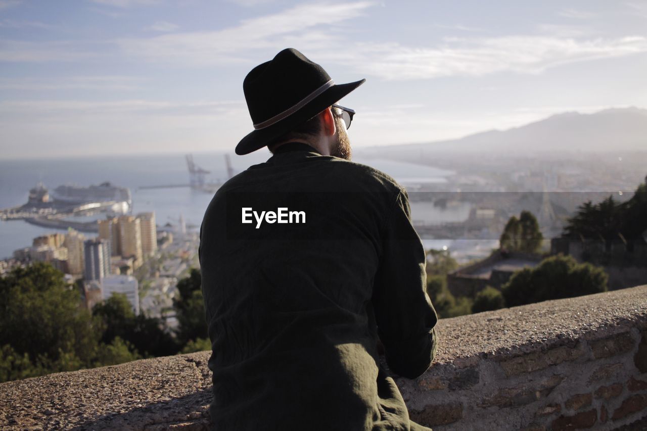 Rear view of man looking at cityscape and bay